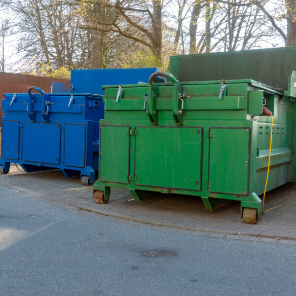 two,garbage,compactors,are,standing,in,the,courtyard,of,a