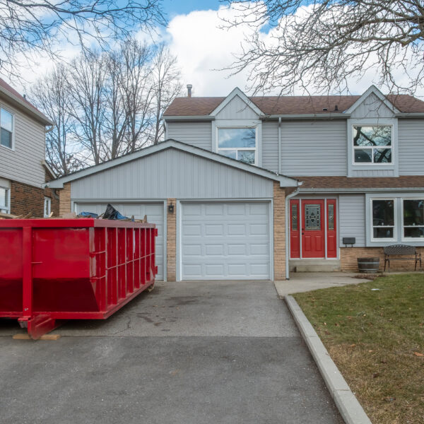 red,dumpster,bin,on,the,driveway,of,a,suburban,house