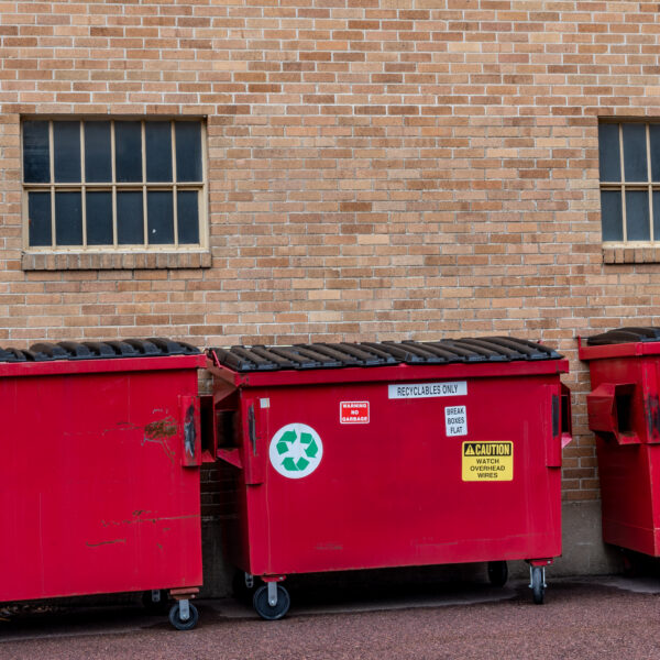 row,of,covered,garbage,bins,along,a,brick,wall,in